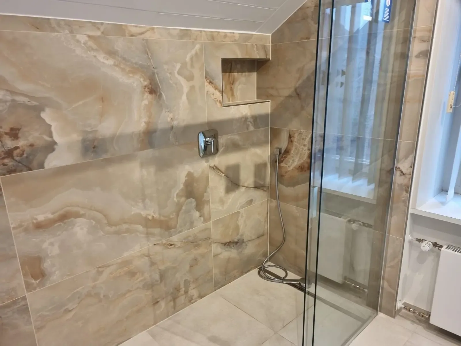 Dusche mit großformatiger Wandverkleidung in Onyxoptik