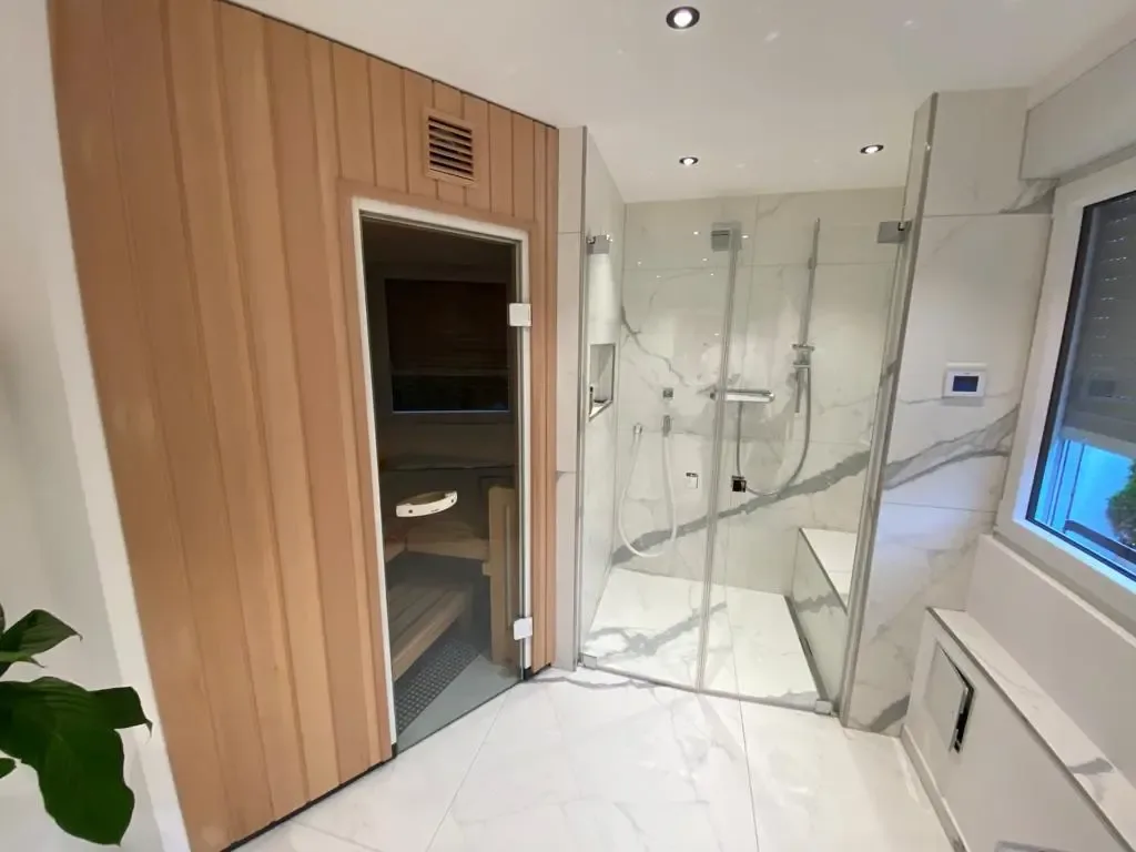 Bodengleiche Dusche mit Glasabtrennung neben einer Sauna