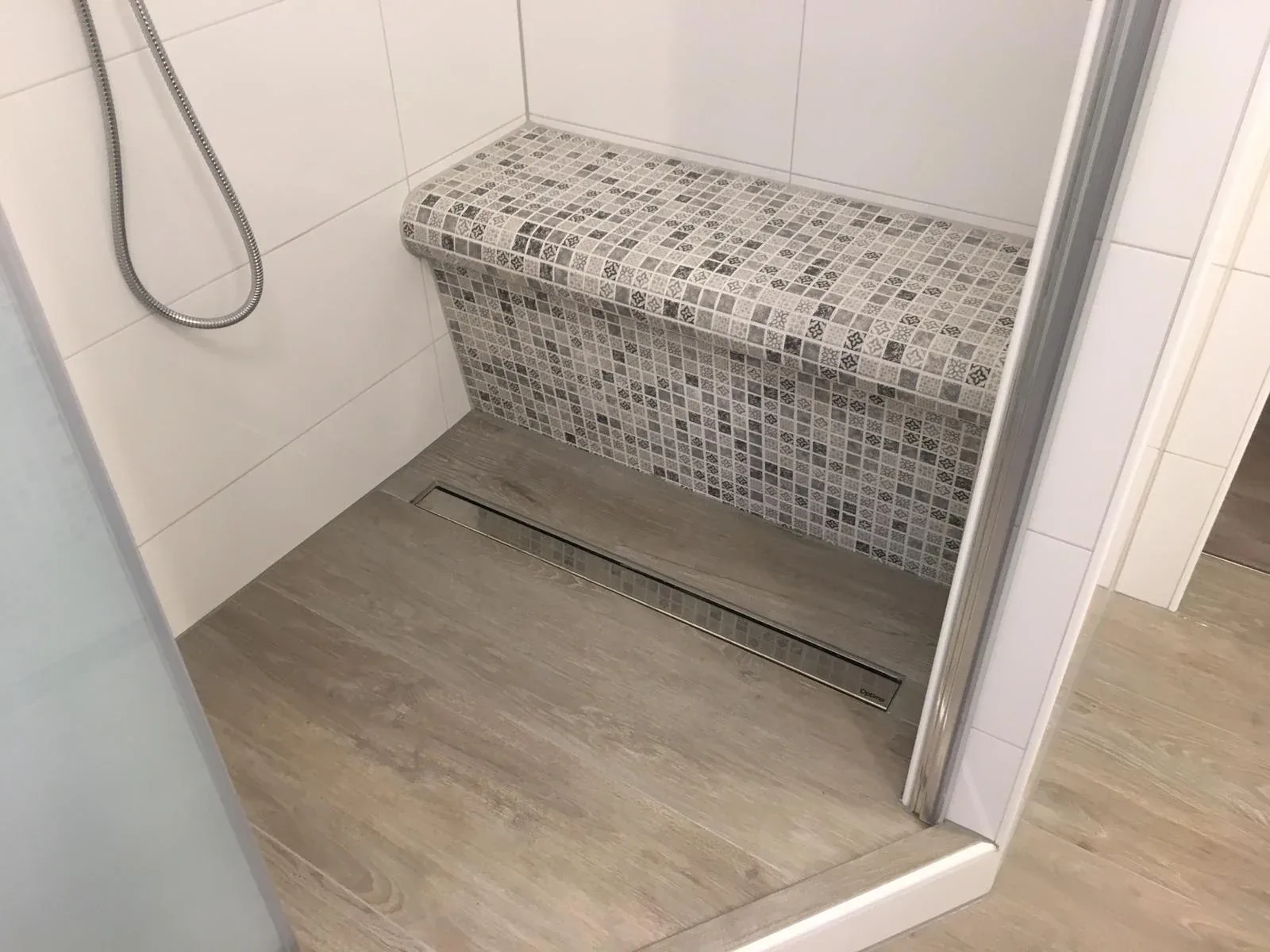 Geflieste Sitzbank mit kleinteiligem Mosaik im Duschbereich