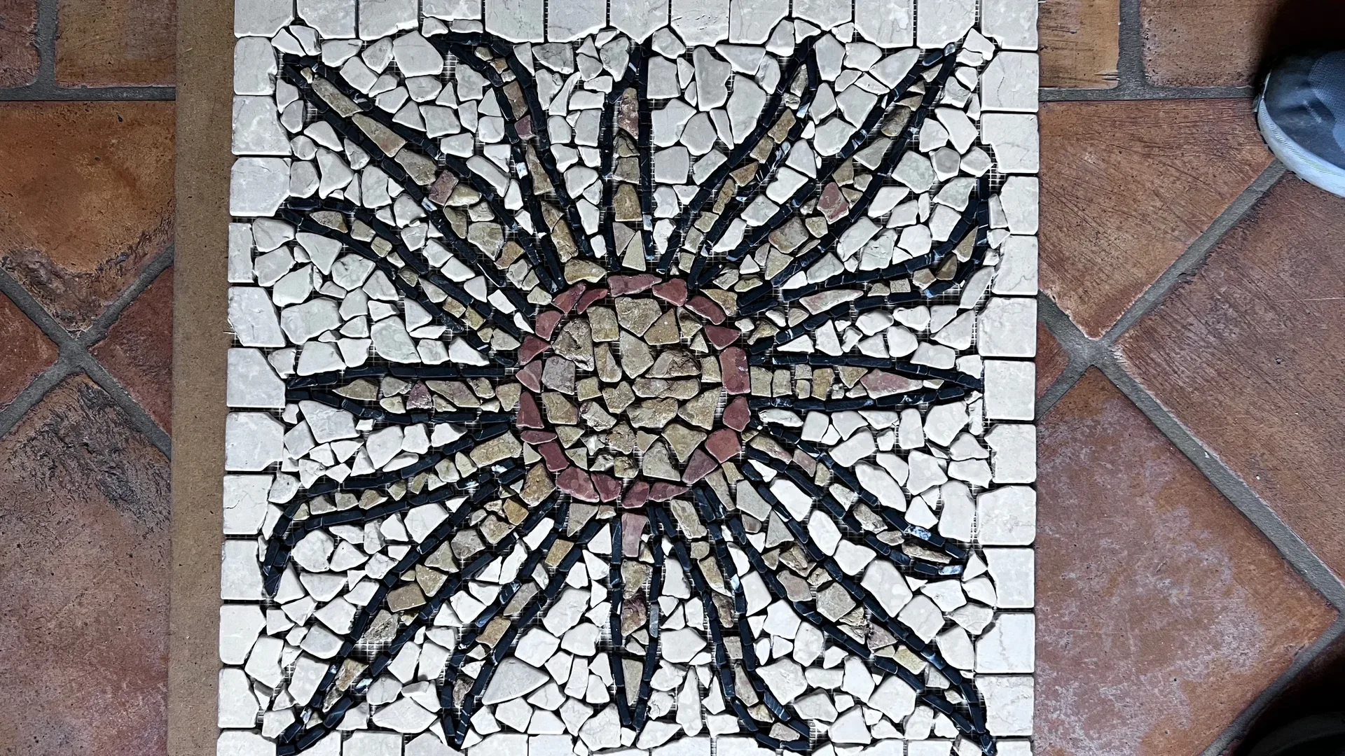 Mosaik mit floralem Muster in hellen und dunklen Steinen