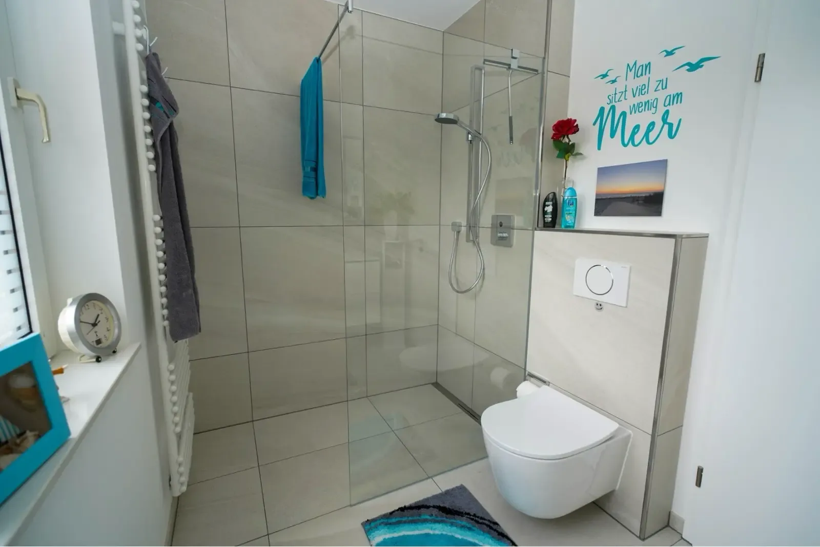 Bodengleiche Dusche mit Glasabtrennung neben einem Wand-WC