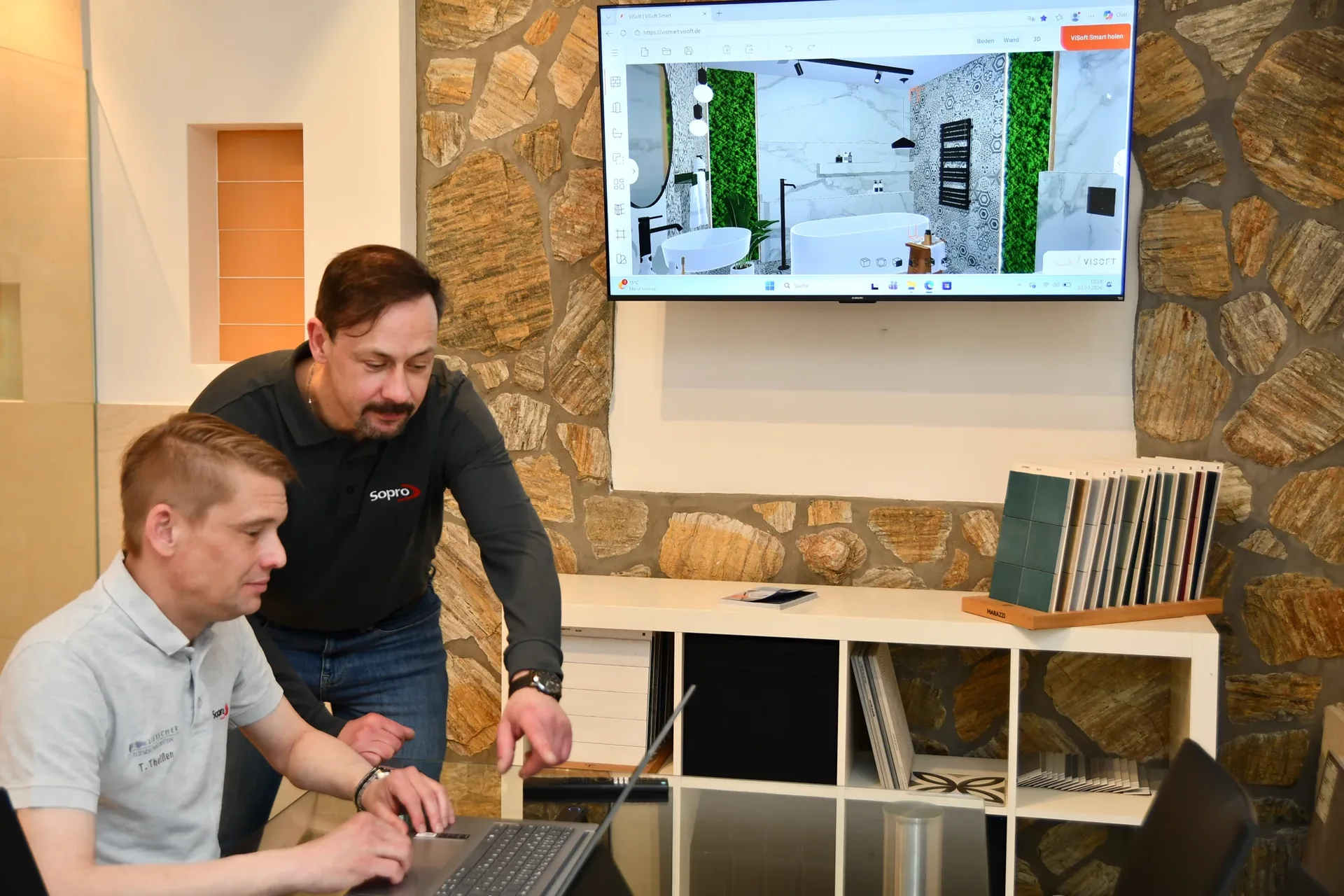 Gemeinsame 3D-Badplanung am Laptop mit Badentwurf auf dem großen Bildschirm