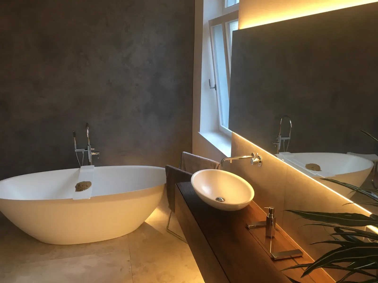 Freistehende Badewanne und runde Waschschale vor einem Holzwaschtisch