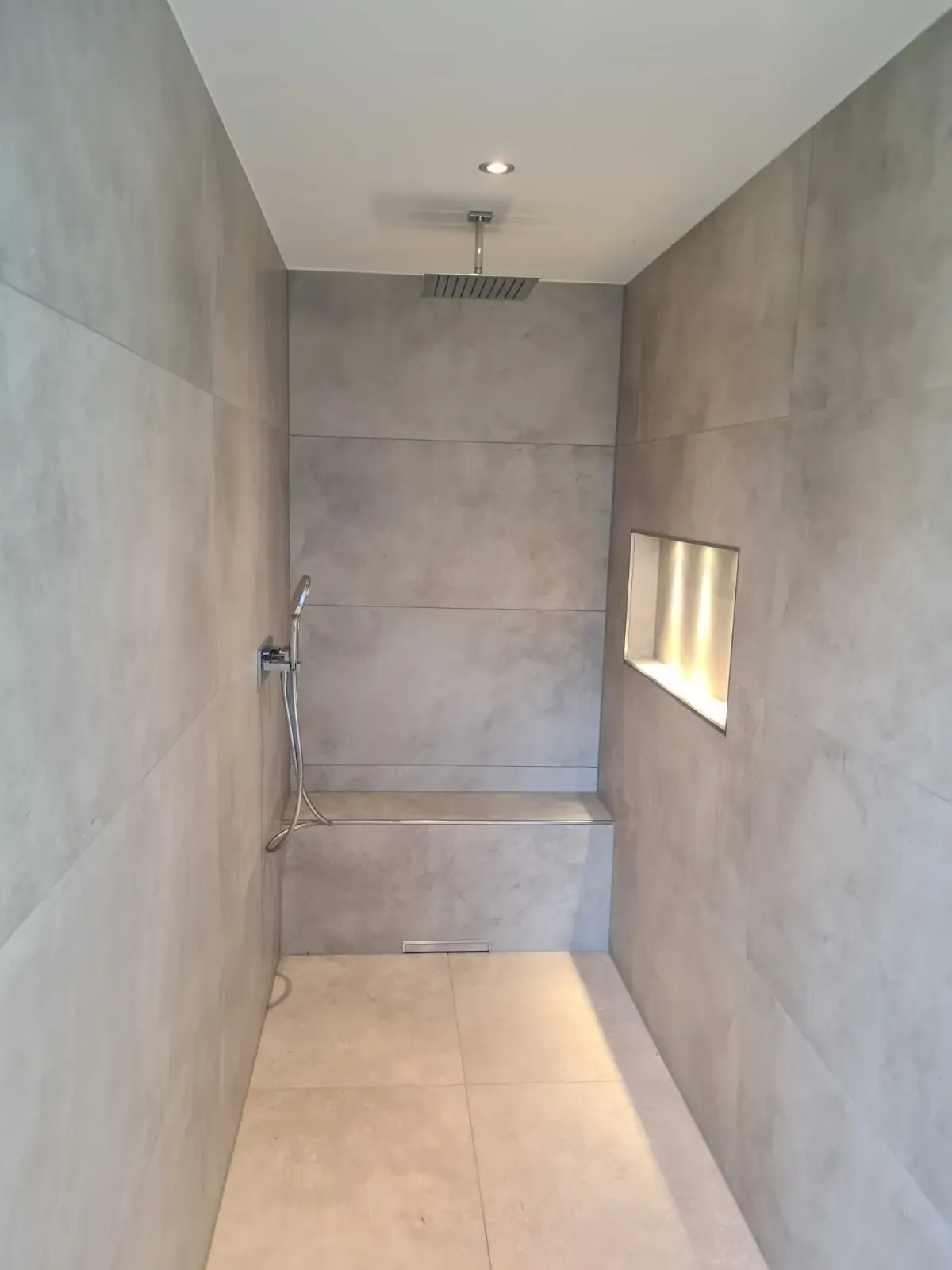 Geflieste Dusche mit Sitzbank und beleuchteter Nische