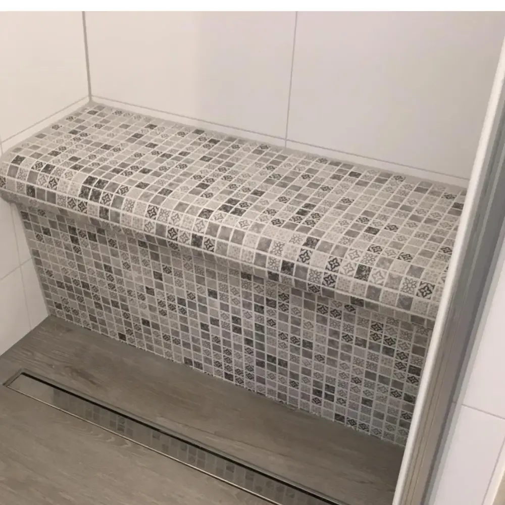 Mit kleinteiligem Mosaik geflieste Sitzbank im Duschbereich