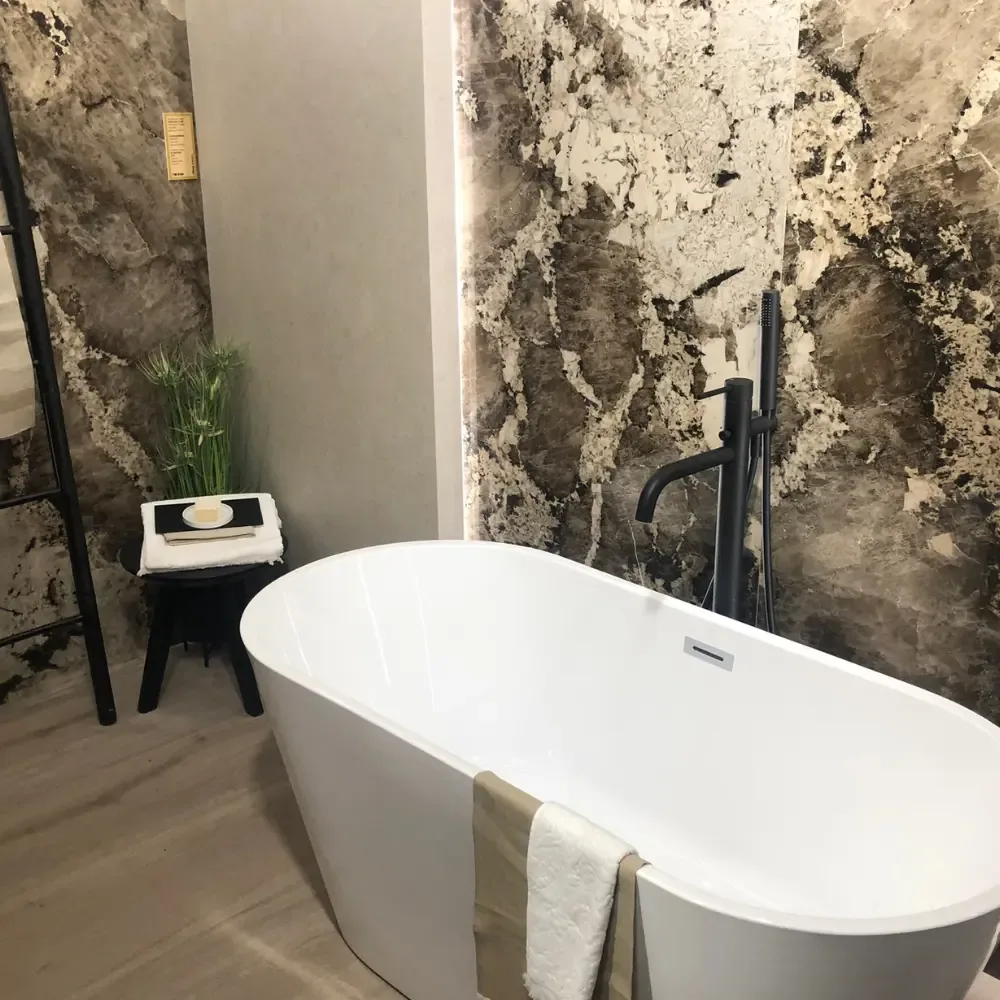 Freistehende Badewanne vor einer markant geaderten Wandverkleidung