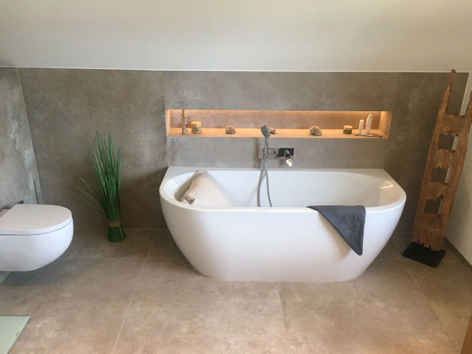 Freistehende weiße Badewanne vor einer beleuchteten Wandnische Freistehende weiße Badewanne vor einer beleuchteten Wandnische